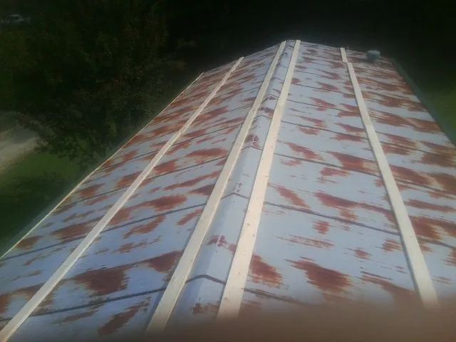 Rusted metal roof panels with new wood purlins before replacement — Storm Damage Roof Repair in Norris by Roofing Brothers