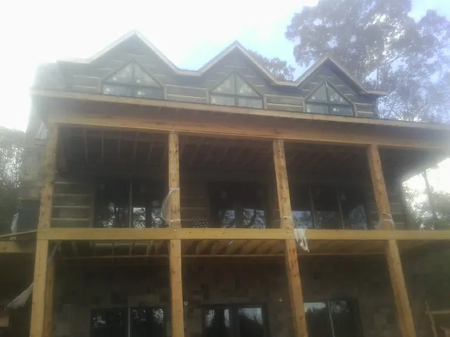 Dormers and porch framing on a large log home under construction — Roof Coating work by our crew in Norris
